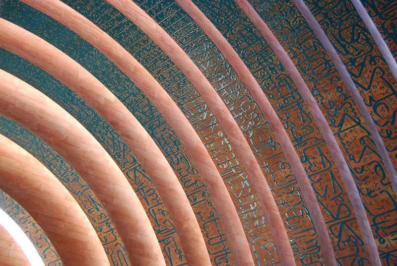Close-up of curved timber ribs with turquoise ceramic tiles inscribed with calligraphy between the beams