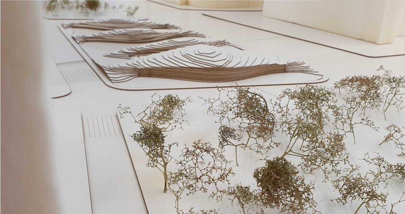 Angled view of the model with miniature trees positioned around the layered roof structure