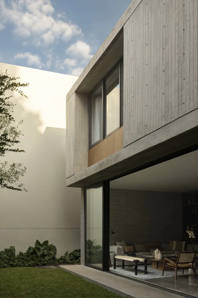 Courtyard view of the concrete and timber upper volume cantilevering over floor-to-ceiling glazing below