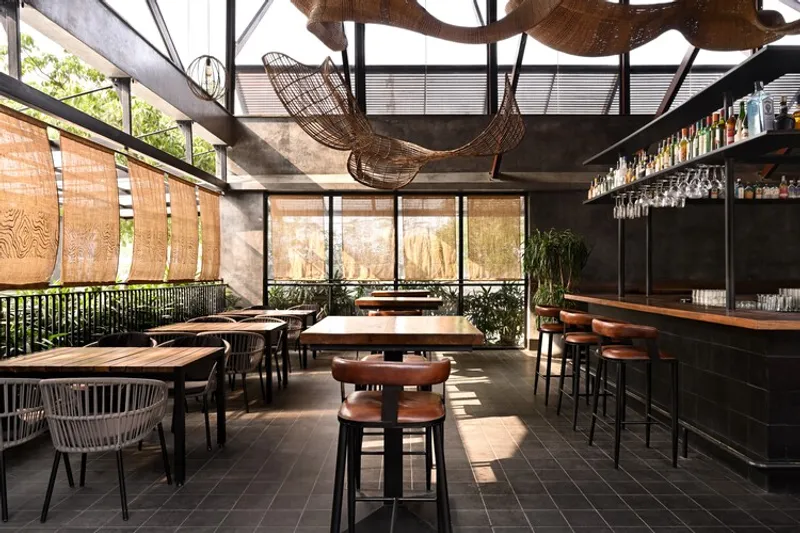 Restaurant interior with exposed timber ceiling beams and woven sculptural light fixtures suspended overhead