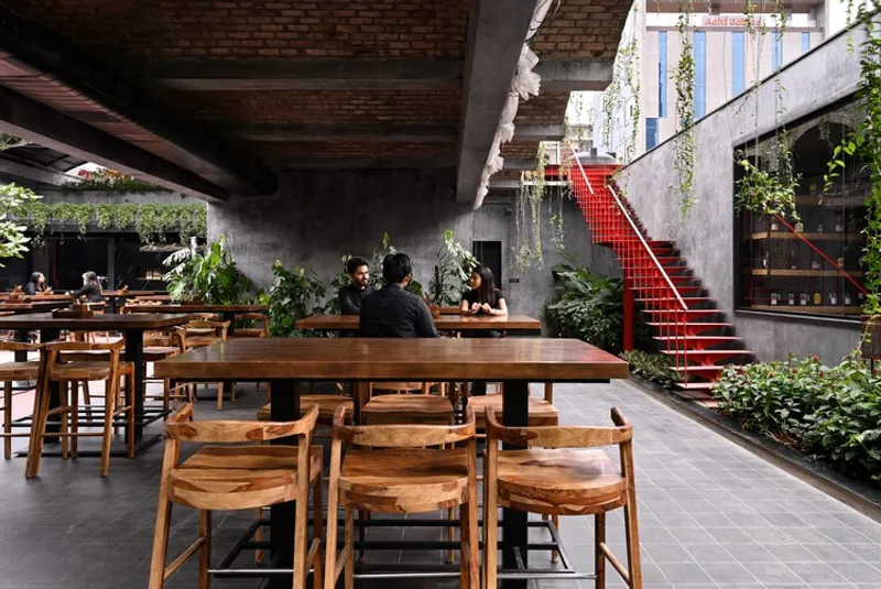 Long timber dining table beneath partial brick ceiling with red steel staircase in background