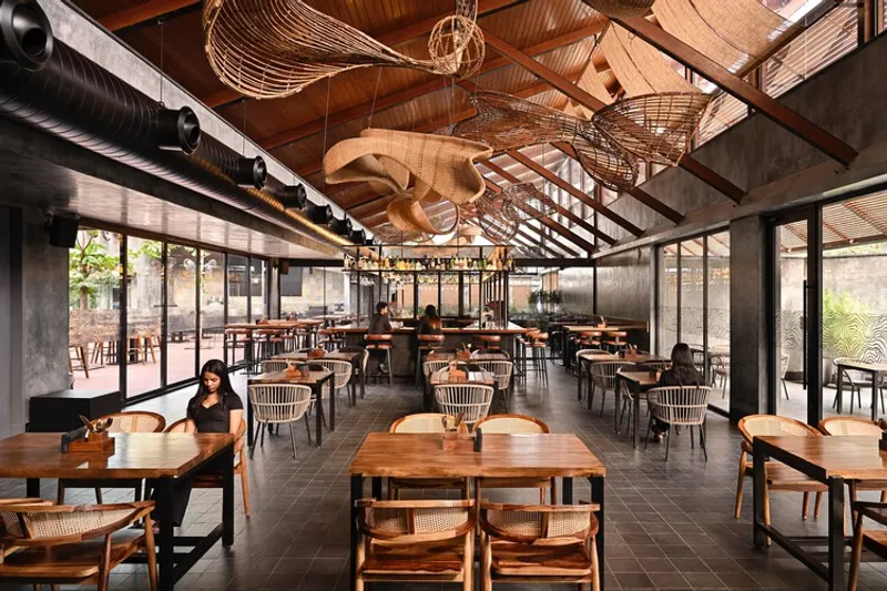 Dining hall with sloped timber ceiling and sculptural woven fish forms suspended from rafters