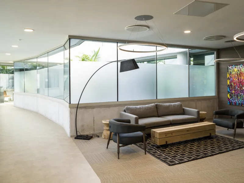 Curved reception desk and seating area with frosted glass partitions and arc floor lamp