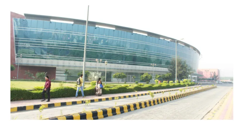 Curved glass facade at street level with pedestrians walking along the planted median