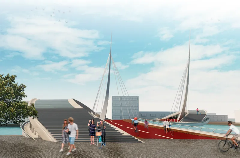Cable-stayed pedestrian bridge with red deck connecting waterfront areas as cyclists and pedestrians cross