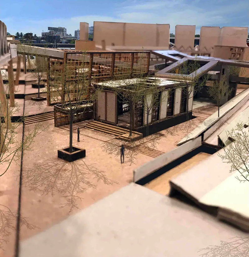 Physical model showing courtyard buildings with timber screens and planted trees under midday sun