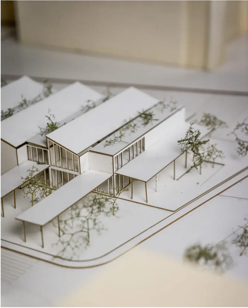 Angled view of the physical model revealing interlocking volumes with glazed walls and planted courtyard spaces