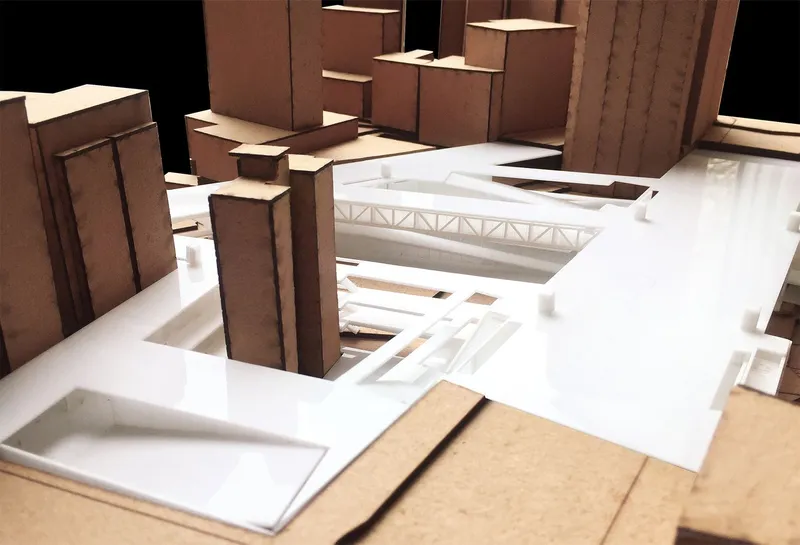 Physical model detail showing the exposed white truss structure spanning between adjacent buildings