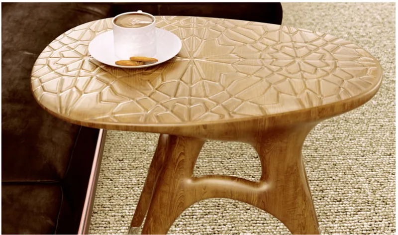 Close-up of the carved geometric pattern on the oval tabletop with a coffee cup resting on it