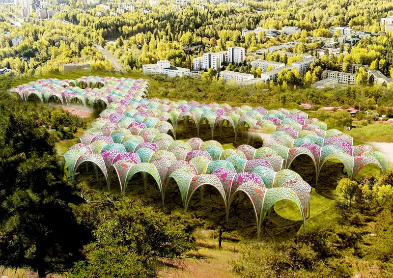 Aerial view of the clustered vaulted pavilions with cellular canopies across a forested clearing
