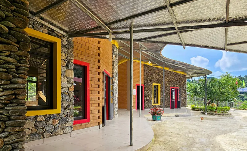Covered courtyard with stone and brick walls, yellow window frames, and woven bamboo canopy overhead