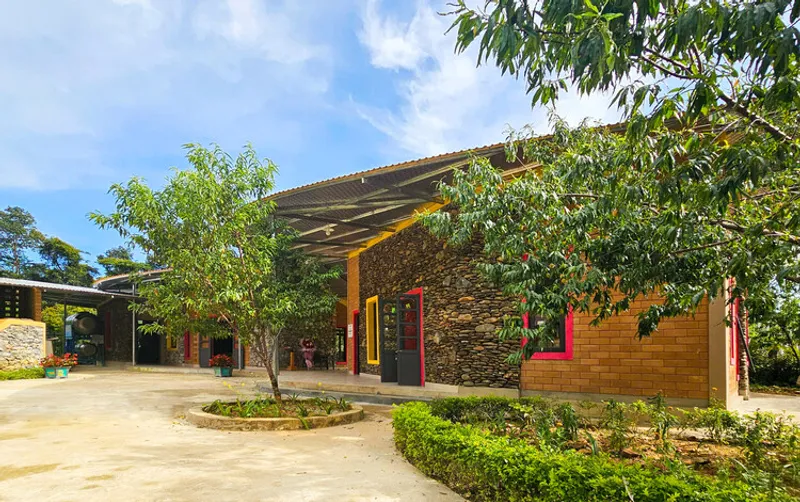Courtyard view showing timber block walls with red window frames and trees under a blue sky