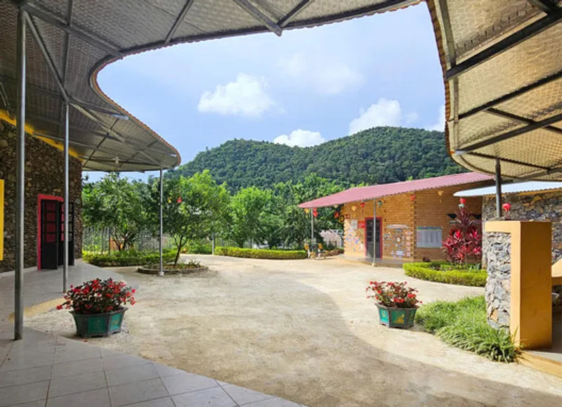 Covered walkway with curved roof framing a view toward the hillside and adjacent pavilions