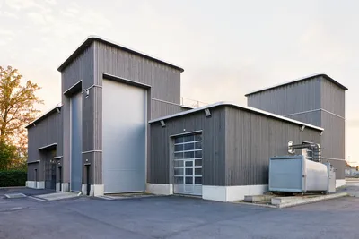 This architectural image showcases a modern industrial building with a corrugated metal facade. The 