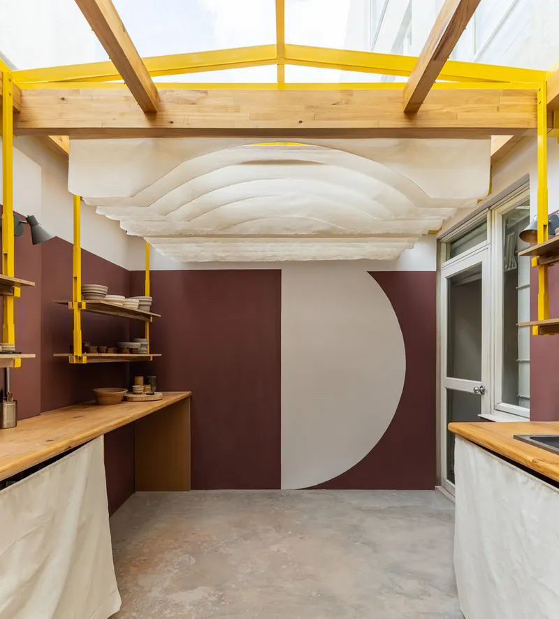Interior view of layered plywood ceiling waves above timber counters and shelving