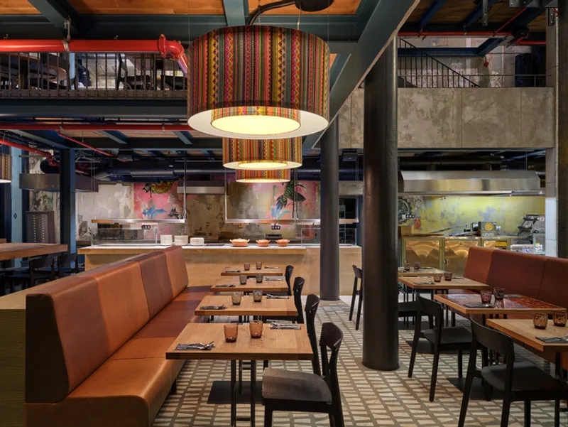 Dining area with orange upholstered banquettes and exposed structural beams painted red and blue