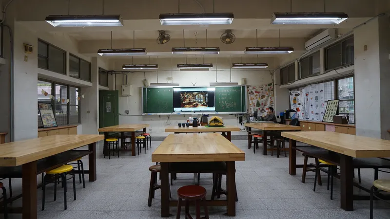 Classroom interior with terrazzo floor, timber work tables, suspended fluorescent lights and green chalkboards