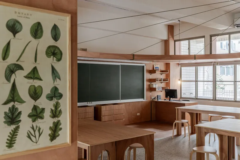 Classroom interior with timber benches, botanical chart on wall, and blackboard beneath exposed timber ceiling beams