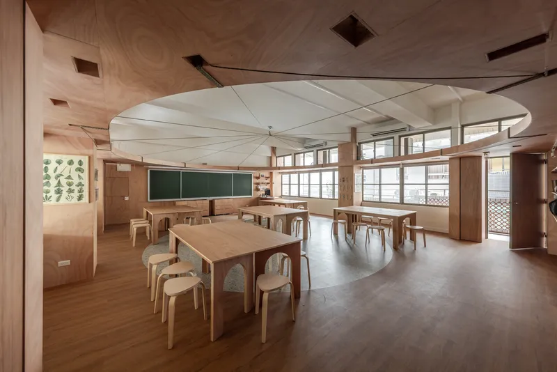 Wide view of classroom with curved fabric ceiling canopy, timber tables, and wraparound windows