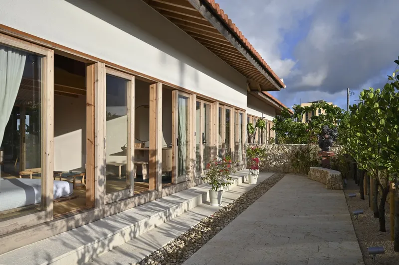 Covered walkway with timber framed glass doors casting dappled shadow patterns on the concrete path
