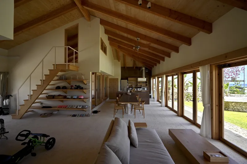Open-plan living space with timber staircase and full-height glazed doors overlooking a garden