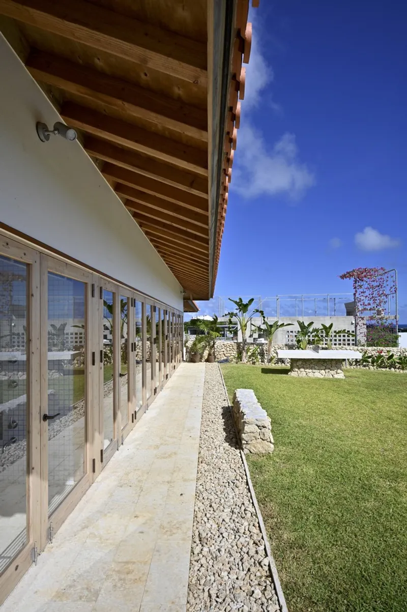 Exterior walkway with exposed timber rafters, limestone paving and a gravel drainage strip beside the lawn