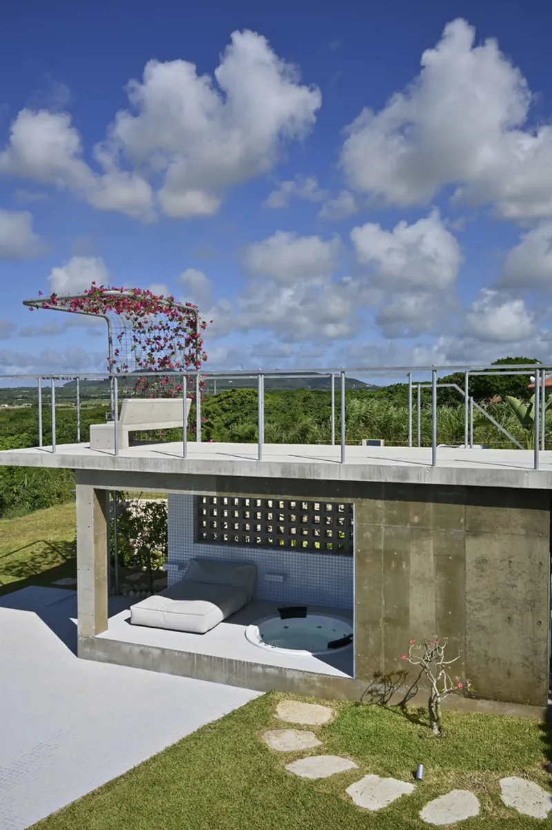 Sunken seating area with concrete walls and rooftop terrace above overlooking distant green landscape