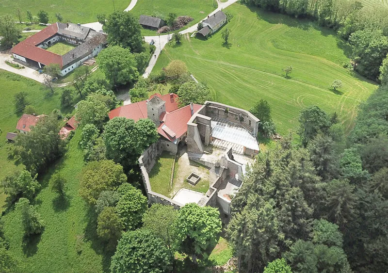 Aerial view of the courtyard compound with red tile roofs nestled among deciduous trees in summer