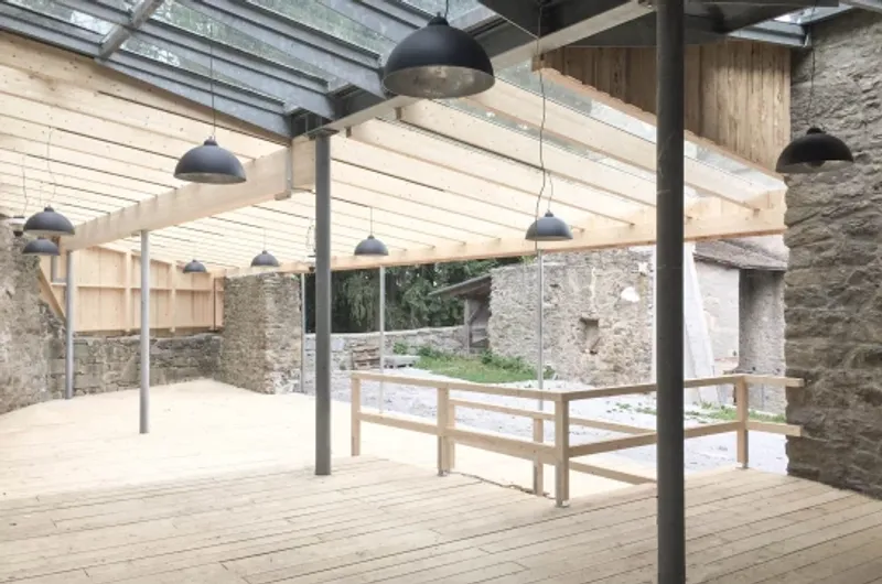 Interior space with steel columns and timber ceiling beams beneath a glazed skylight opening to courtyard