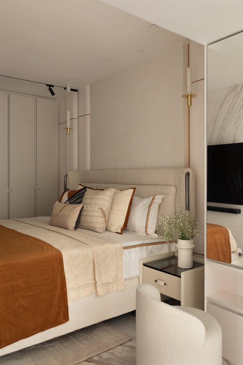The master bedroom, with a tall linen headboard framed by paired brass-and-alabaster pendants.