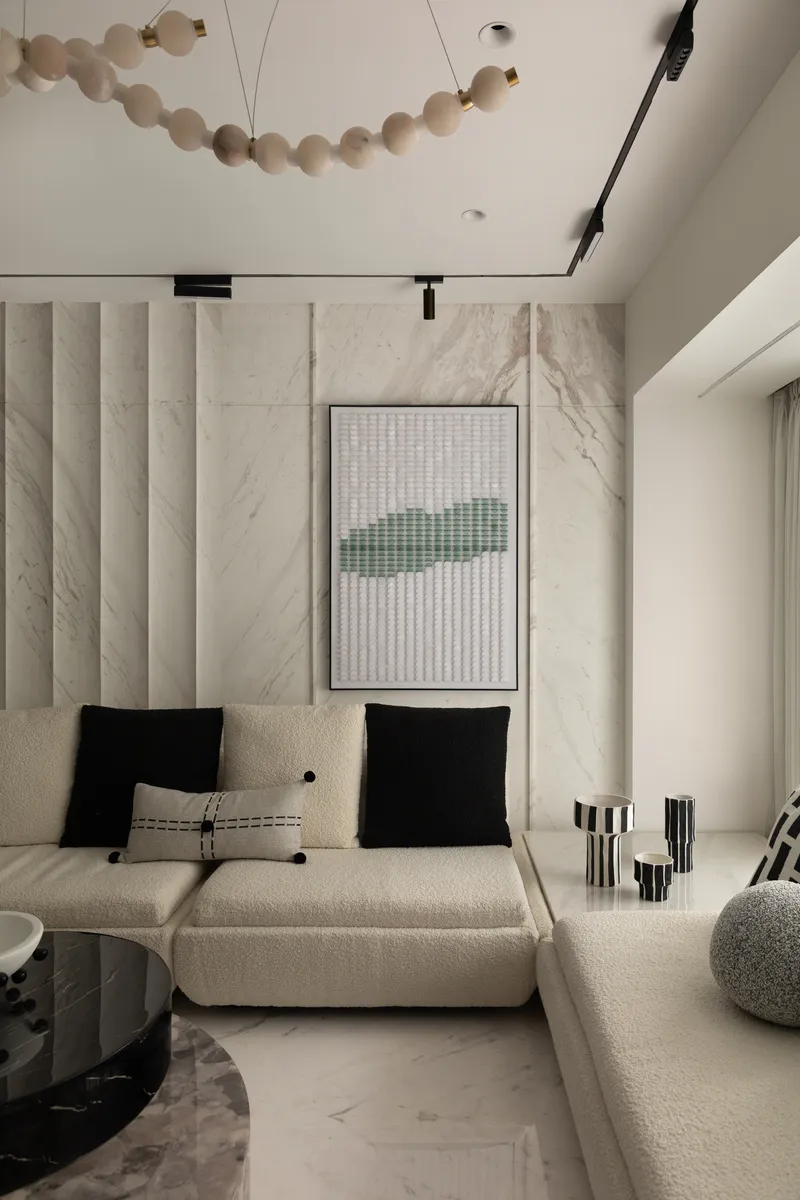 Bouclé modular seating and graphic black-and-white cushions against the fluted marble backdrop.