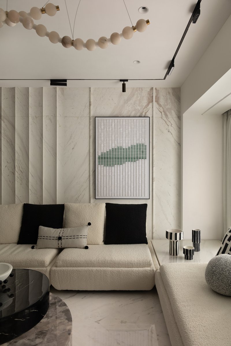 Bouclé modular seating and graphic black-and-white cushions against the fluted marble backdrop.