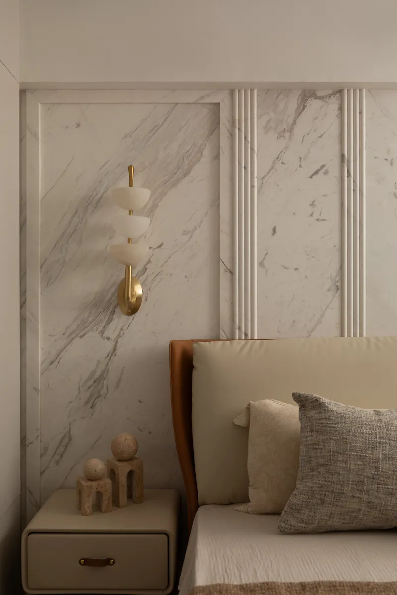 A bedside detail of the brass-and-alabaster sconce against the book-matched marble panel.