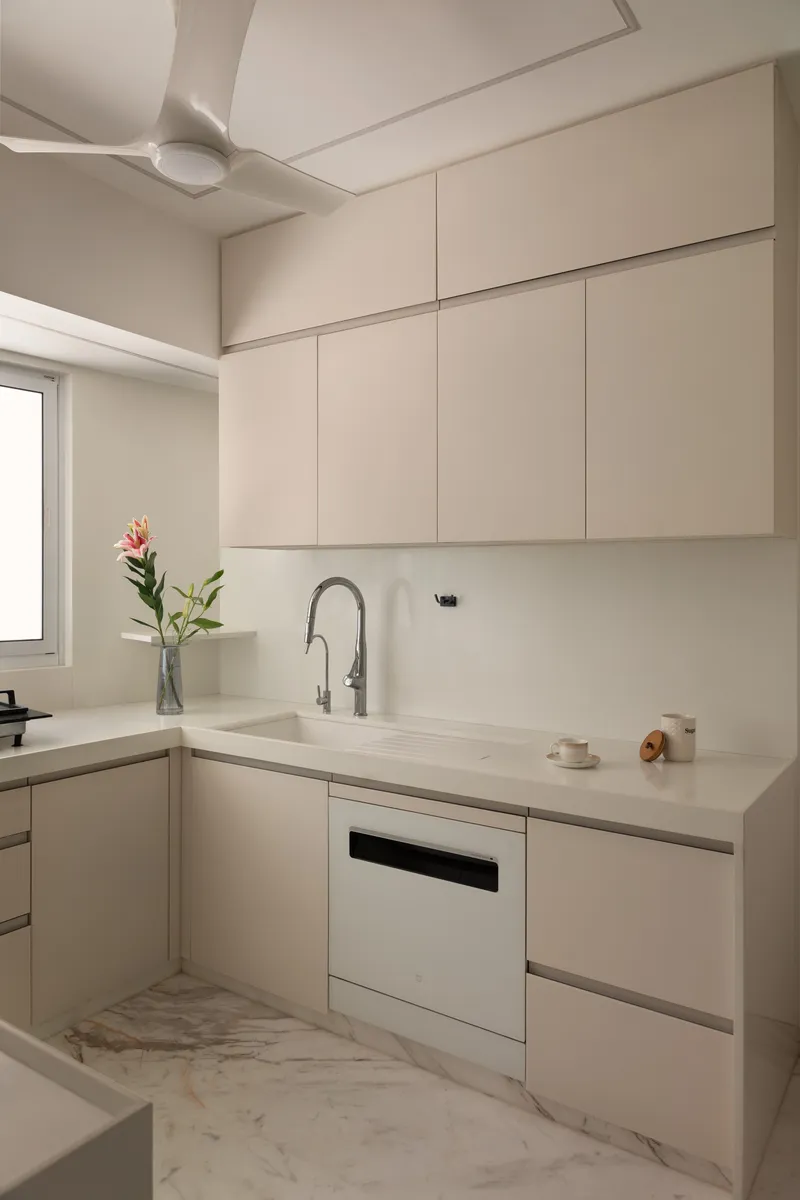 The L-shaped working kitchen continues the cream palette.