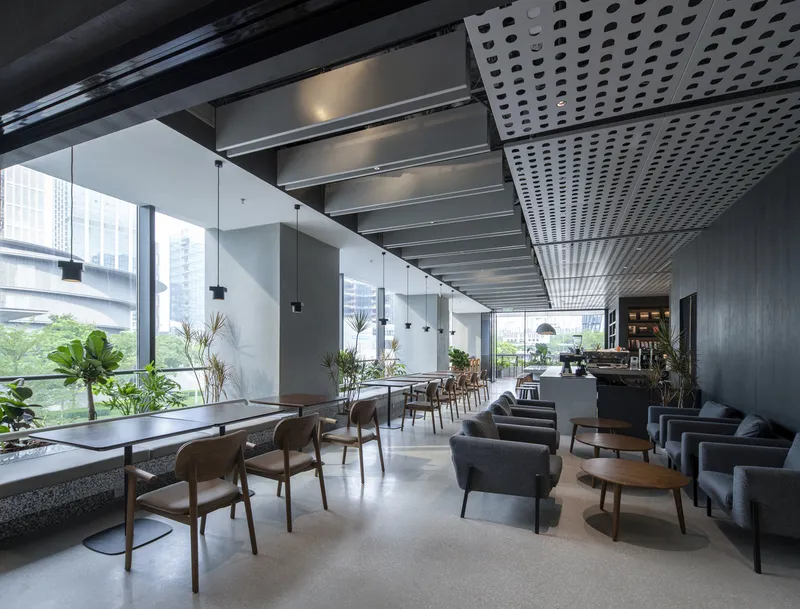 Cafe seating area with floor-to-ceiling windows, pendant lights and perforated acoustic ceiling panels