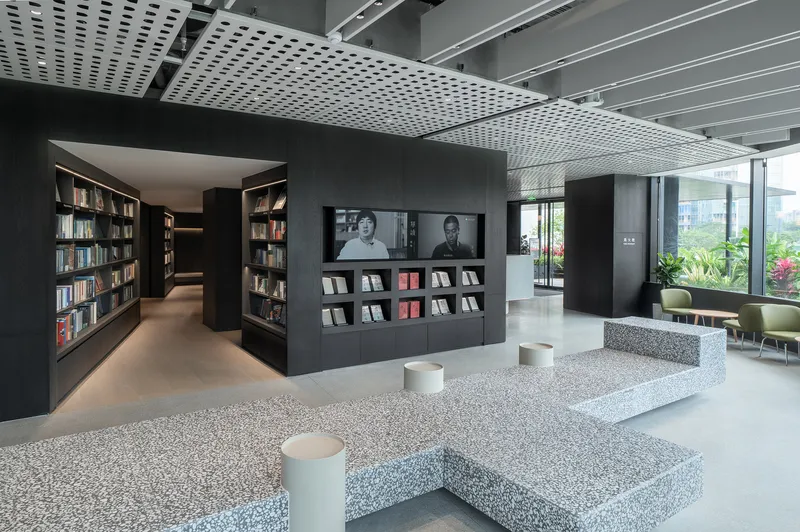 Interior view of terrazzo seating platforms and display kiosks beneath a white perforated metal ceiling