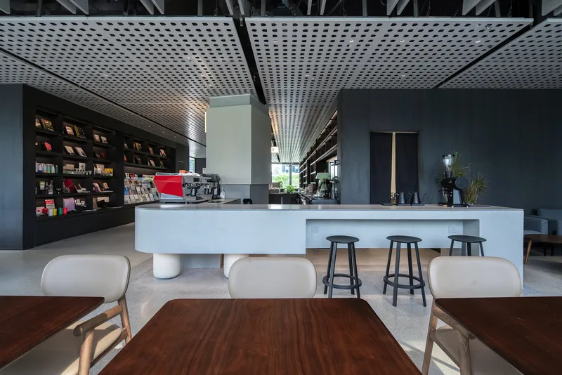 Cafe counter with cylindrical white legs and timber floor inset under radiating perforated ceiling pattern