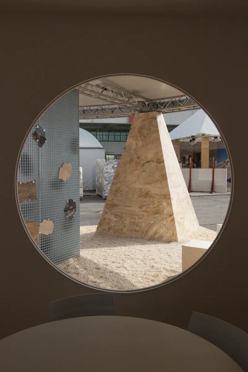 Circular portal framing view of plywood column and glass mosaic wall with material samples