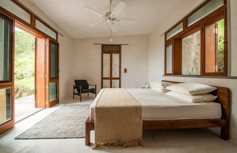 A traditionally outfitted room with teak-and-marble shutters and a lounge chair by Mahendra Doshi. The bed wears a ghondagi wool blanket from Maharashtra.