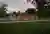 This architectural image showcases a modern pavilion situated in a park setting. The pavilion featur