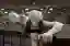 The image showcases a sculpture of a human figure seemingly trapped in a vise, set against the backd