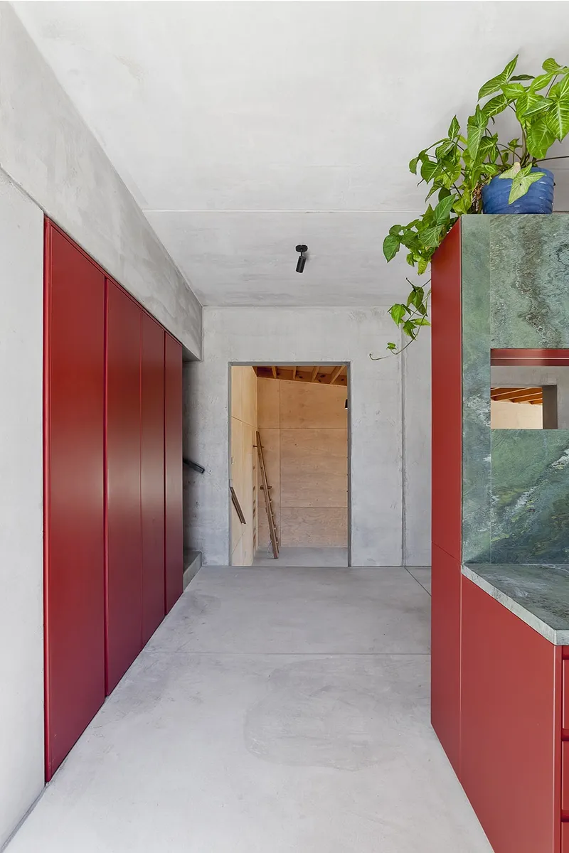 Contrast between concrete and red furniture © Mariana Bisti