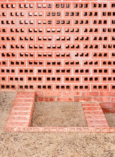 The image showcases a brick wall with a perforated design, creating a rhythmic pattern of openings. 