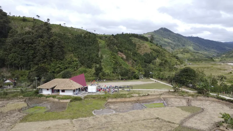 The pavilion complex surrounded by terraced agricultural fields under a cloudy sky with forested mountains behind