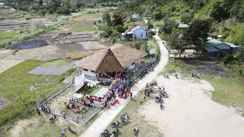 Aerial view showing the thatched roof among rice terraces with a community gathering below