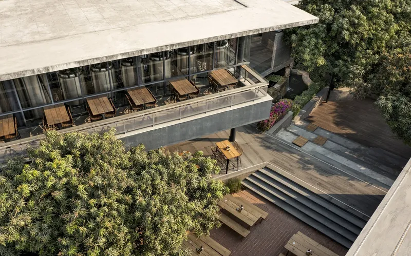Aerial view of tiered terraces with concrete steps, timber decking, and planted trees between building volumes