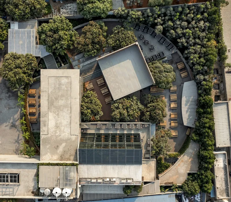 Aerial view showing concrete roof pavilion surrounded by rows of outdoor seating and mature trees