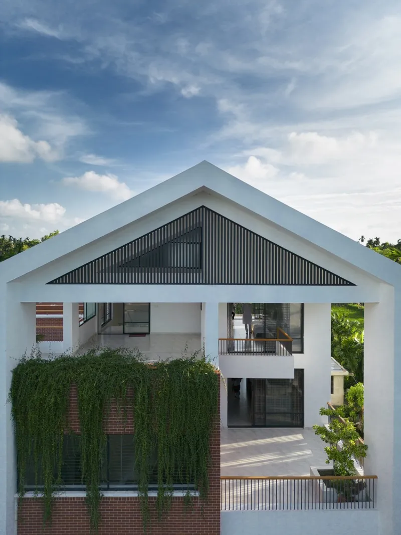 White gable frame enclosing a dark corrugated panel with brick and green climbing vines below