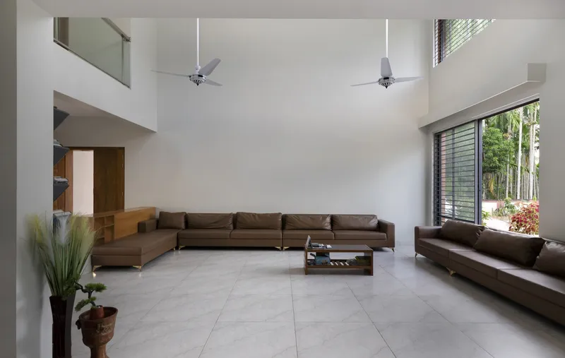 Double-height living room with mezzanine overlooking sectional seating and pale tile flooring