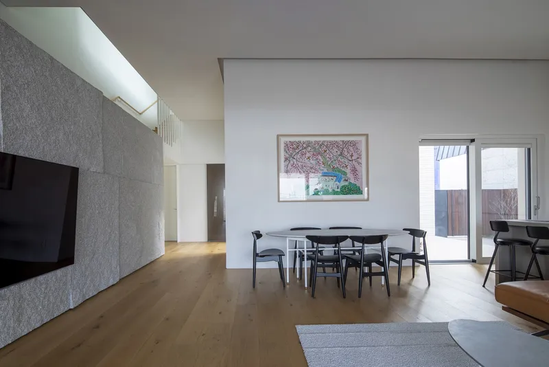 Open living and dining space with oak floors and skylight above grey stone wall